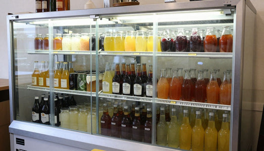 A perfectly organized glass-front commercial cooler with drinks sorted by type and color, showcasing an efficient FIFO system.