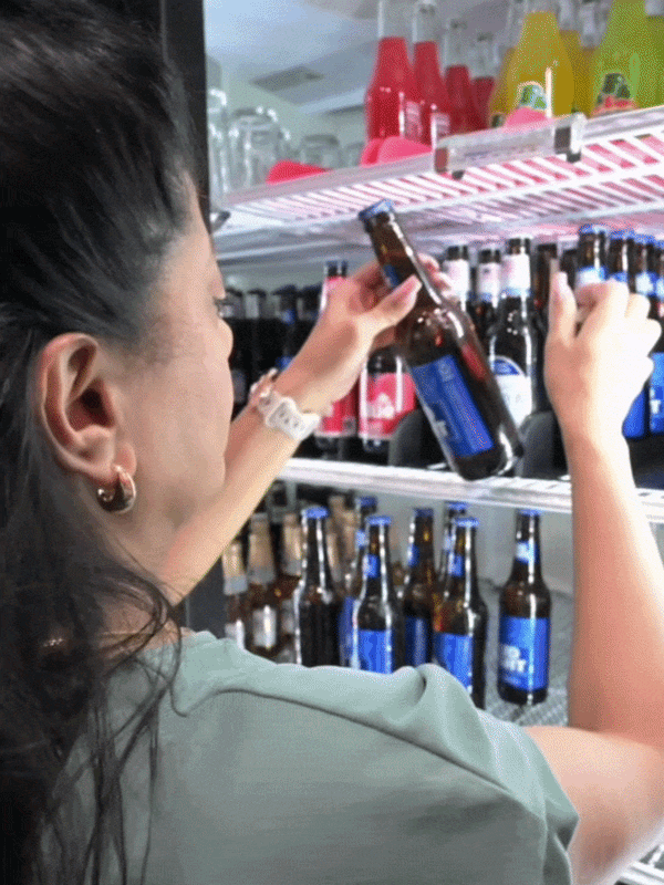 Bartender organizing beer bottles in a commercial cooler using FIFO beverage system for efficient bar fridge organization
